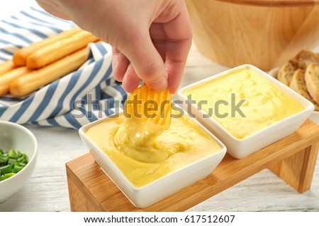 Woman hand dipping chip in beer cheese dip