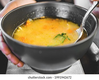 Woman Hand Eating Chicken Soup In Black Bowl In Cafe