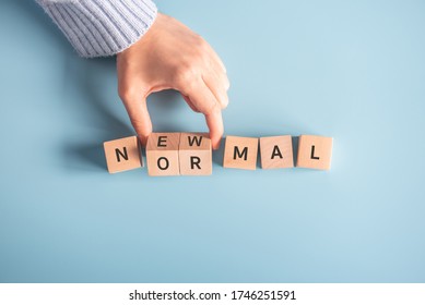 Woman hand flipping wooden cubes with NEW NORMAL word. Adapting to new life or business post-lockdown after coronavirus pandemic. Business with social distancing personal hygiene. - Shutterstock ID 1746251591