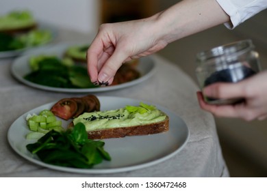 A Woman Hand Giving Black Sesame On Avocado Toast