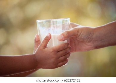 Woman Hand Giving Glass Of Milk To Child In Vintage Color Tone