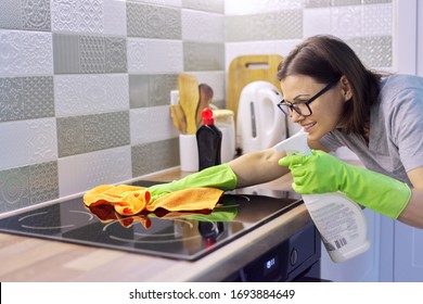 Woman hand in gloves cleaning kitchen electric ceramic hob, polishing glass with microfiber cloth