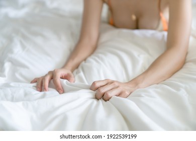 Woman hand grasping white sheet. Couple making love or having sex in bedroom.
