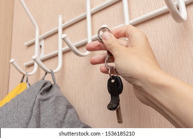 Woman Hand Hanging Keys On A Ring On A Coat Rack Hook In A Hallway, Anteroom At Home, Home Safety And Security Concept