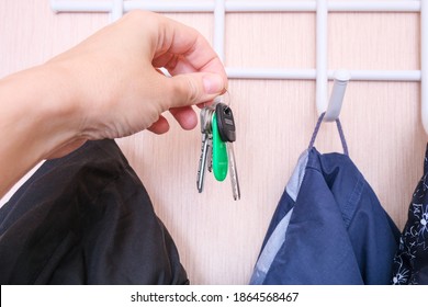 Woman Hand Hanging Keys On A Ring On A Coat Rack Hook In A Hallway, Anteroom At Home, Home Safety And Security Concept.