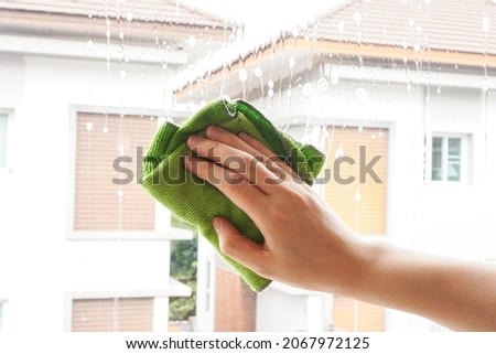 woman hand hold green microfiber cloth or rag to clean window by wipe on glass cleaner bubble , housewordk concept Foto stock © 