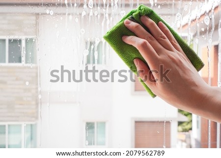 woman hand hold green microfiber cloth or rag to clean window by wipe on glass cleaner bubble , housewordk concept Foto stock © 
