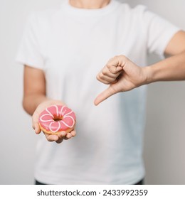 woman hand hold pink Donut, choose stop eating sweet is Unhealthy ealthy food. Dieting control, Weight loss, Obesity, eating lifestyle and nutrition concepts