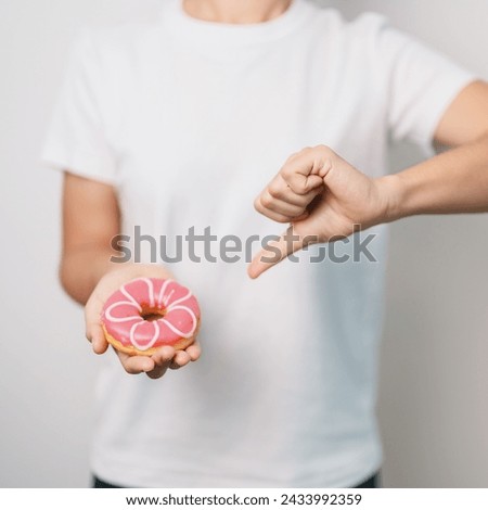 woman hand hold pink Donut, choose stop eating sweet is Unhealthy ealthy food. Dieting control, Weight loss, Obesity, eating lifestyle and nutrition concepts