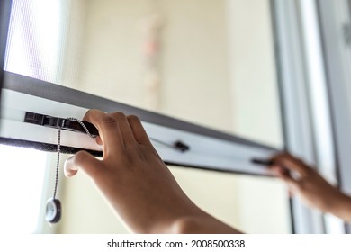 Woman hand hold retractable pleated insect screen holder to open or close the window ,mosquito nets - Shutterstock ID 2008500338