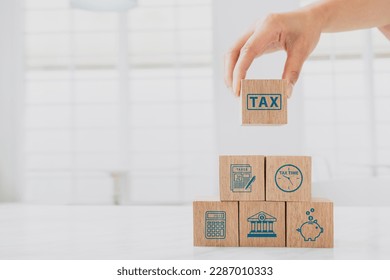 Woman hand hold wooden block with tax icon. Calculation tax return, vat, personal income tax, tax payment. Business and finance concept. 