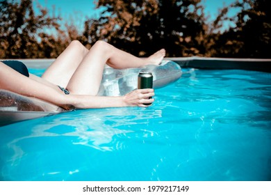 Woman Hand Holding Beer Can Floating On The Blue Pool Water And Relaxing. Copy Space