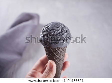Woman hand holding black ice-cream in hand