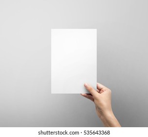 Woman Hand Holding Blank Paper Sheet A5 Size Or Letter Paper On Grey Background.