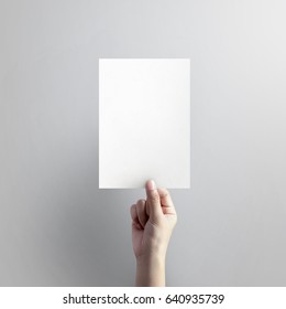 Woman Hand Holding Blank Paper Sheet A5 Size On Grey Background.