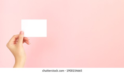 Woman Hand Holding Blank White Business Card, Discount Or Flyer On Pink Background With Copy Space. Template For Your Design