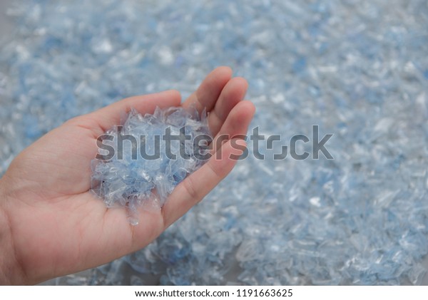 Woman\
hand holding Bottle flake,PET bottle flake,Plastic bottle\
crushed,Small pieces of cut blue plastic\
bottles