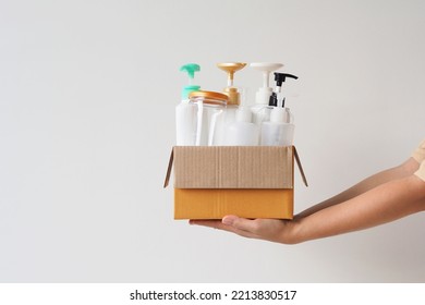 Woman hand holding box of plastic bottles and jar for refill liquid soap, shampoo and other products. Zero waste. Reuse reduce recycle concept. Empty space for your text or design.