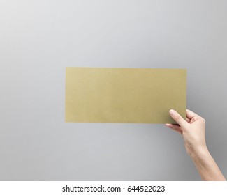 Woman Hand Holding Brown Envelope For Letter Paper On Grey Background.