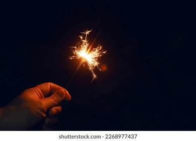 Woman hand holding a burning sparkler. Christmas and new year sparkler holiday background - Powered by Shutterstock