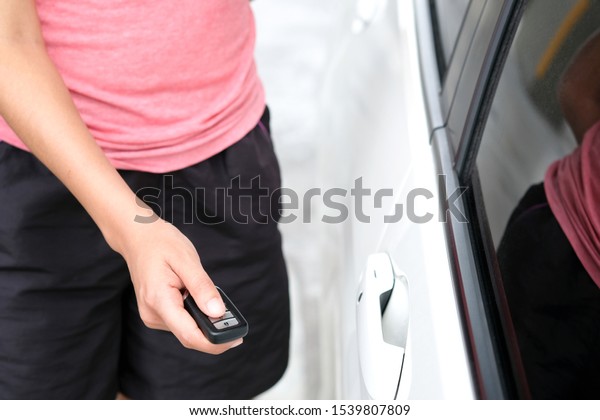 woman hand holding the car remote, he push the\
remote control to open the car\
door