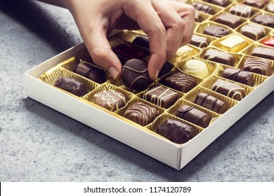 Woman Hand Holding A Chocolate Piece From Various Type In  Box For Valentine's Day