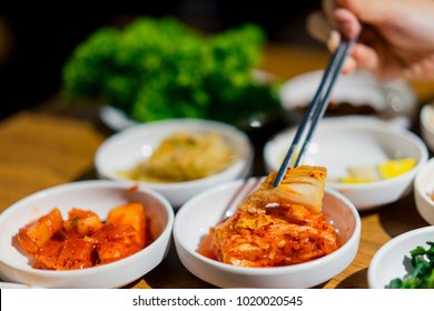 Woman Hand Holding Chopsticks For Eating Kimchi Salad In Restaurant. Korean Food Traditional Kimchi