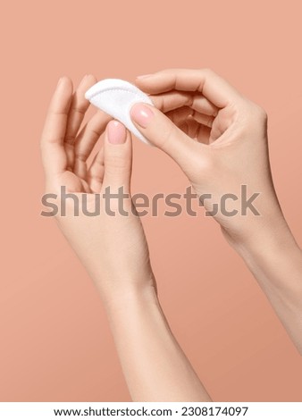 Woman hand holding a clean cotton disk. Applying cosmetic products or pilling nail polish. Fingernail, hand and body care concept. Image for beauty salon, cosmetologist or manicure artist promotion. 