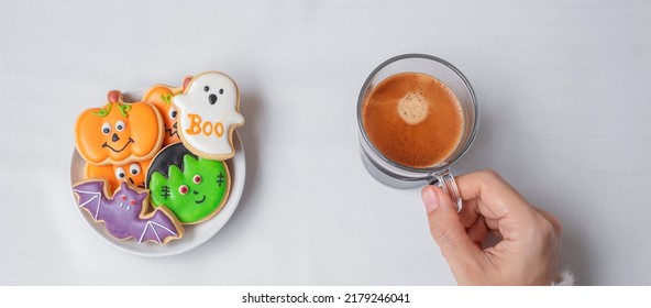 Woman Hand Holding Coffee Cup During Eating Funny Halloween Cookies. Happy Halloween Day, Trick Or Threat, Hello October, Fall Autumn, Traditional, Party And Holiday Concept