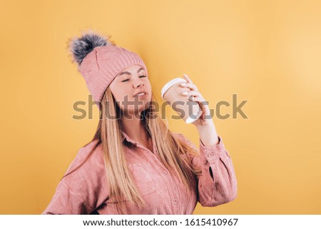 Woman hand holding a Coffee paper cup on yellow background.
