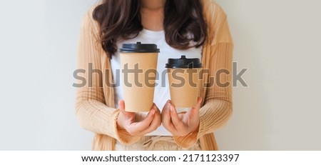 Woman hand holding coffee paper cup on white background. Mockup for you designs.