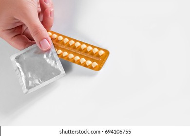 Woman hand holding contraceptive pills and condom. Protection, safe sex. Contraception, birth control. Copy space