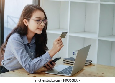 Woman hand holding credit card and using mobile phone and laptop for online shopping. Businesswoman or entrepreneur working. Business, e-commerce, spending money, working from home concept