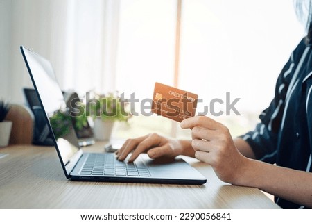Woman hand holding credit card and using laptop at home, online shopping and paying bills, Payment method. 