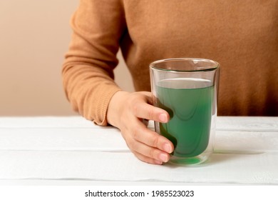 Woman Hand Holding Cup Of Chlorophyll Water On White Table