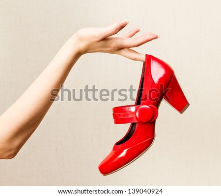 Woman hand holding dress red high heels shoe.