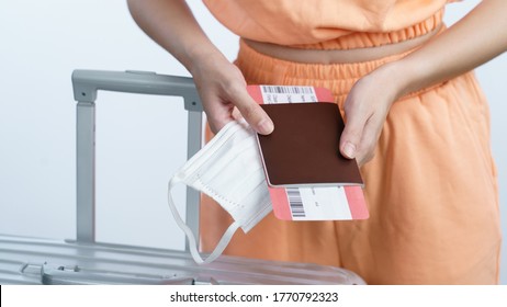 Woman Hand Holding Face Mask Luggage Passport And Boarding Pass, New Normal Travel Concept.(Fake Barcode)