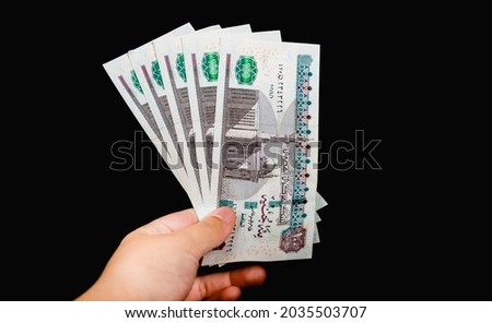 woman hand holding five hundreds  Egyptian bounds isolated on black background