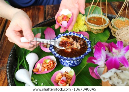 Woman Hand Holding Fresh Lotus Petal Wrapped Appetizer while Scooping Out Spicy Dip