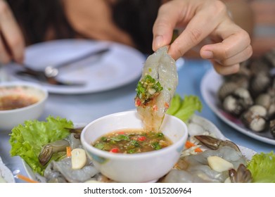 Woman hand holding fresh raw shrimp dipped with spicy sauce side with garlic - Shutterstock ID 1015206964