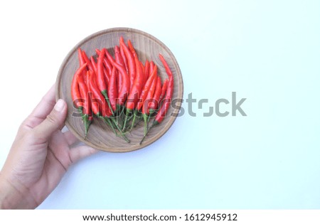 A woman hand holding Fresh red  chili in a wooden dish