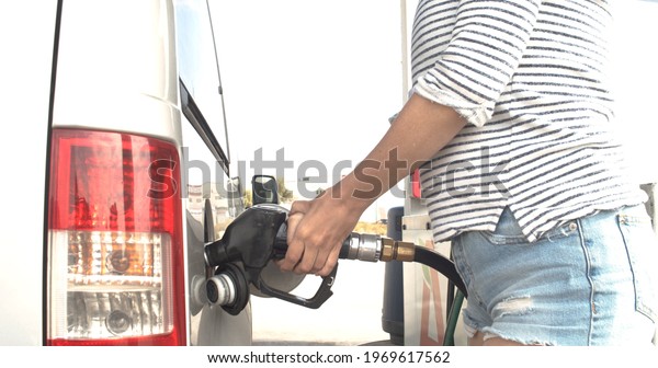 Woman hand holding fuel nozzle and put in to\
automobiles tank to filling diesel gas fuel at gas station in slow\
motion shot.	
