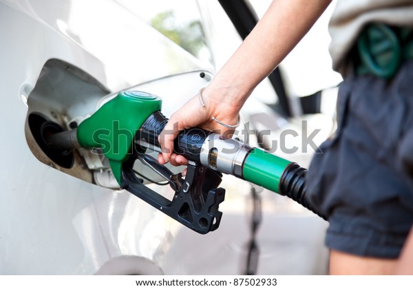 woman hand holding fuel nozzle and refuel car in\
gas station