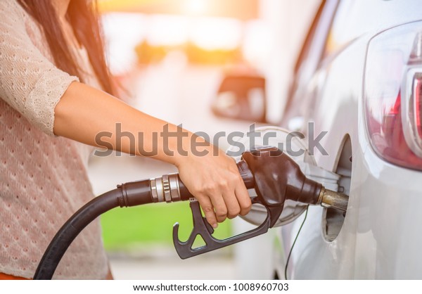 Woman  hand\
holding a fuel pump at a\
station.