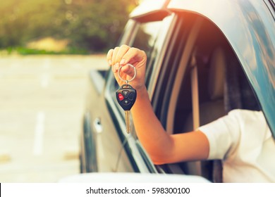 Woman hand holding, giving key of auto car, motor vehicle. Concept of dealership, first, used or new car. People is dealer person, salesman, agent, buyer or customer. To sale, rent, buy or purchase.
