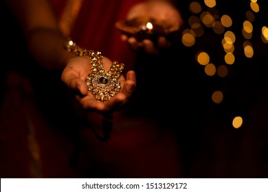 Woman hand holding gold necklace jewelry on Diwali Festival or Dhanteras. Concept for newly weds bride jewellery, festive gift, diwali bumper offer, holiday pamphlet, banner, advertisement.