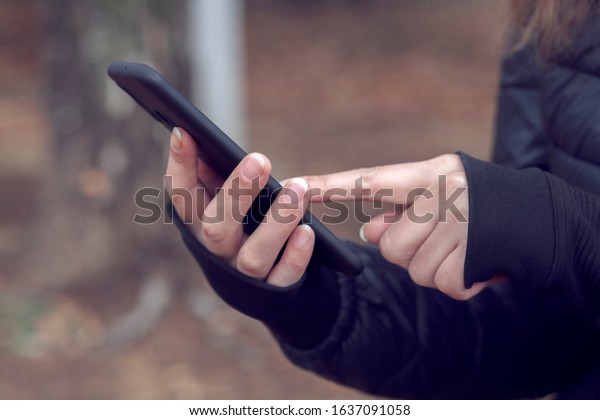 woman hand holding her smart phone in the park with blur background.