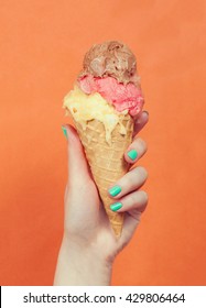 Woman Hand Holding Ice Cream On Orange Background