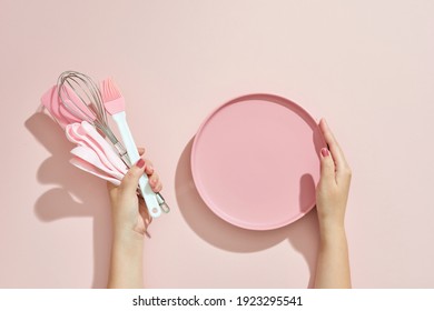 Woman Hand Holding Kitchen Utensils On Pink Background. Baking Tools