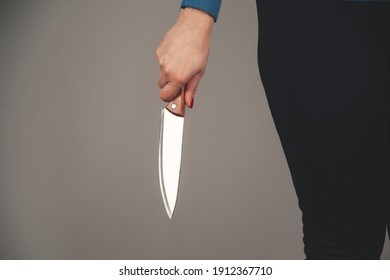 woman hand holding knife in back on gray background
